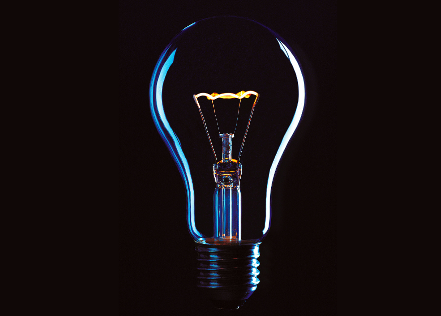 Close-up of a glowing light bulb against a dark background.