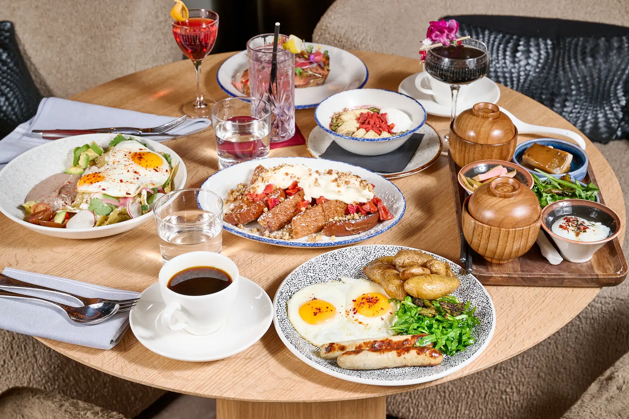 Table set with a variety of brunch dishes, including eggs, sausage, fresh greens, and drinks at The Jay Hotel.